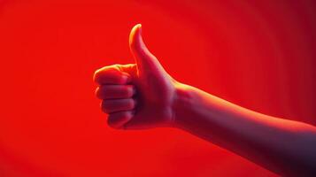 A Hand Giving a Thumbs Up Gesture Against a Red Background photo