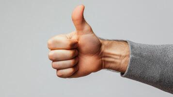 A Hand Gesturing Thumbs Up with a Grey Sleeve photo
