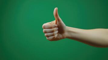 A Person's Hand Giving a Thumbs Up Gesture Against a Green Background photo