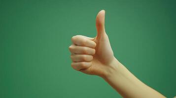 A Hand Gesturing Thumbs Up Against a Green Background photo