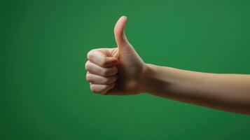 A Hand Giving a Thumbs Up Gesture Against a Green Background photo