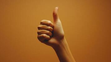 A Hand Gesturing a Thumbs Up Against a Brown Background photo
