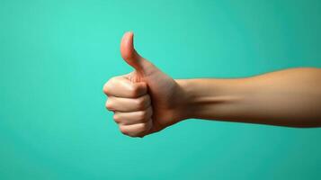 A Hand with Thumb Extended in a Thumbs Up Gesture Against a Teal Background photo