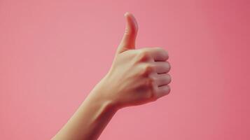 A hand giving a thumbs up gesture against a pink background photo