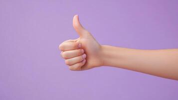 Close-up of a hand giving a thumbs up gesture against a purple background photo