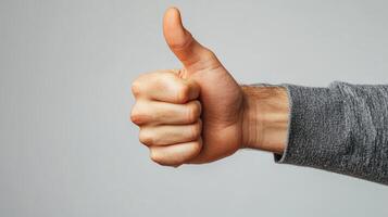 A hand with thumb extended, giving a thumbs-up gesture photo