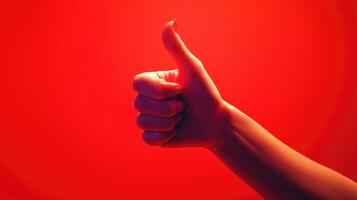 Hand Giving a Thumbs Up Gesture Against a Red Background photo