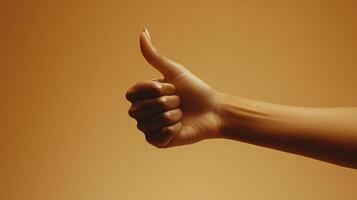 A Hand Giving a Thumbs Up Gesture Against a Tan Background photo