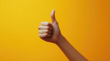 A Hand Gesturing Thumbs Up Against a Yellow Background photo