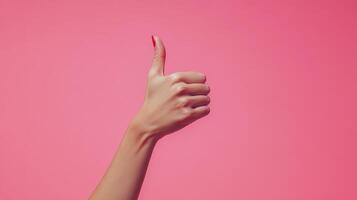 A Hand with Red Nail Polish Giving a Thumbs Up Gesture Against a Pink Background photo