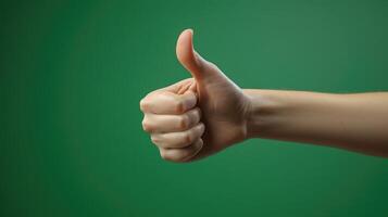 Hand Giving a Thumbs Up Gesture Against a Green Background photo