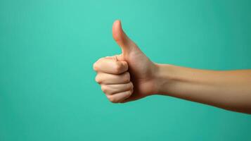 A Hand Giving a Thumbs Up Gesture Against a Teal Background photo