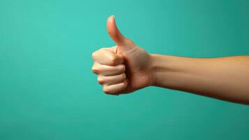 A hand giving a thumbs up gesture against a turquoise background. photo