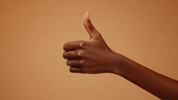 A Hand Giving a Thumbs Up Gesture Against a Tan Background photo