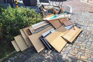 A heap of assorted discarded household items and furniture piled up on a cobblestone street, depicting a bulk waste collection day in an urban environment. photo