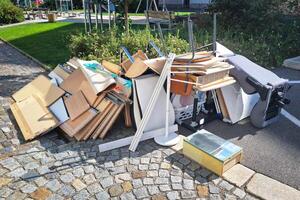 A heap of assorted discarded household items and furniture piled up on a cobblestone street, depicting a bulk waste collection day in an urban environment. photo