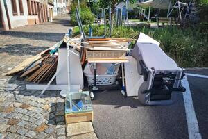 A heap of assorted discarded household items and furniture piled up on a cobblestone street, depicting a bulk waste collection day in an urban environment. photo