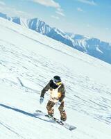 Dynamic picture of man snowboard on the piste ski downhill fast motion in Alps. Active winter holidays, snowboarding downhill in overcast day and mountains background photo