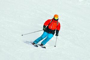 Front view dynamic sports banner of man skier on piste ski downhill fast motion in Alps. Active winter holidays, skiing downhill in overcast day. Ski rides on the track with swirls of fresh snow photo