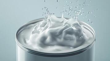 Creamy white substance splashes from a metal canister against a light background photo