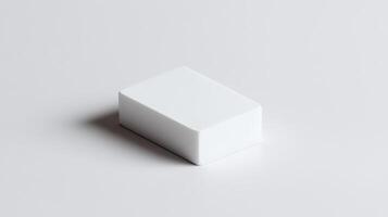 Simple white eraser resting on a clean surface, capturing natural light from above in a minimalistic setting photo