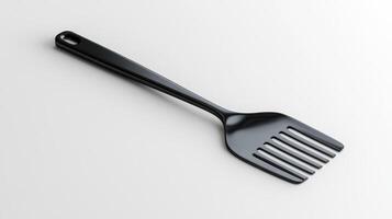 Black plastic spatula resting on a white surface in a well-lit kitchen setting photo