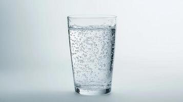 Glass of sparkling water filled with bubbles against a light background photo