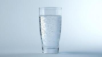 A clear glass filled with sparkling water against a soft blue background photo