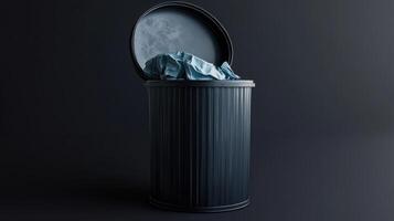A black trash can with crumpled blue fabric peeking out, placed against a dark background photo