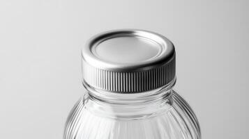 Clear glass water bottle with a silver metal cap on a neutral background photo
