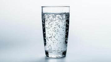 Clear glass filled with sparkling water against a light background photo