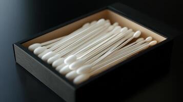 A neatly arranged box of cotton swabs on a dark surface, highlighting their practical use in everyday hygiene and personal care photo