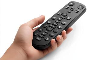 A hand holding a modern black remote control with numerous buttons on a white background photo