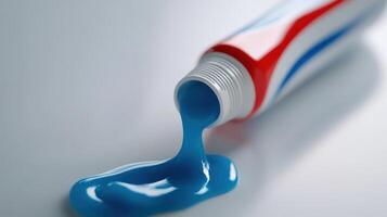 Blue toothpaste pouring out of a squeezed tube on a light surface photo