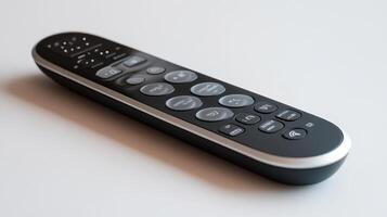 A sleek modern remote control resting on a light surface, showcasing multiple buttons for various functions photo