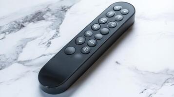 Black remote control on a marble countertop with clear buttons for various functions photo
