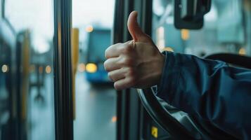 Bus Driver Giving Thumbs Up While Operating Vehicle on Urban Route During Early Morning Commute photo