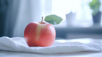 Fresh Red Apple With Green Leaf Resting on White Fabric Tablecloth in Bright Interior Light photo