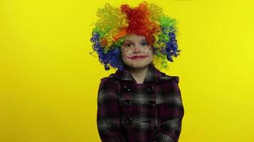 Little child girl clown in colorful wig making silly faces, looks with eyes in different directions video