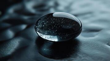 Close-Up Of A Black Droplet Resting On A Smooth Surface In Soft Natural Light photo