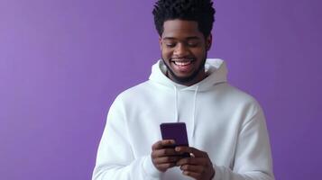 Young man smiling while using a smartphone against a purple background photo