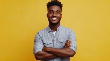 Young man smiling confidently with crossed arms in front of a yellow background photo