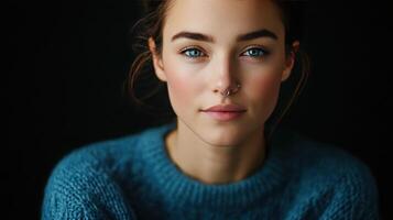Young woman with blue eyes and a septum piercing wearing a cozy sweater during a close-up portrait session indoors photo