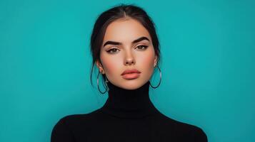 Young woman poses elegantly against a bright turquoise background while wearing a black turtleneck and hoop earrings in a studio setting photo
