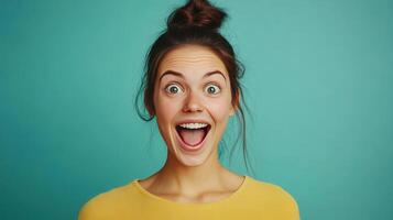 Cheerful young woman with a bun hairstyle expressing happiness against a bright blue background photo