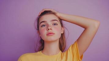 Young woman with long hair posing against a purple background while holding her head in a casual manner indoors photo