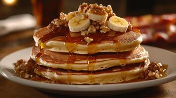 Delicious stack of pancakes topped with bananas, walnuts, and syrup served at a cozy breakfast spot in the morning photo