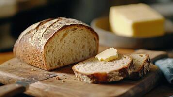 Freshly baked artisanal bread with a pat of butter on a wooden cutting board in a rustic kitchen setting photo