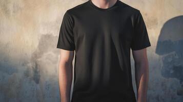 Man wearing a black t-shirt stands against a textured wall during golden hour light in an outdoor setting photo