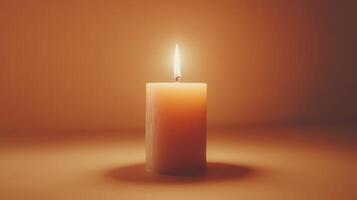 A single glowing candle casts a warm light against a soft backdrop in a tranquil setting photo